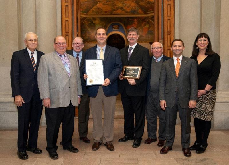Group photo of award recipients holding framed award certificate